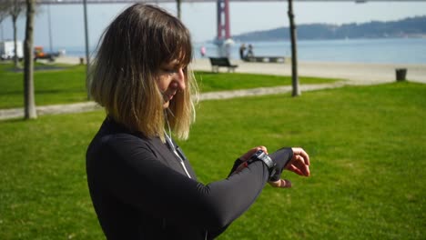Athletic-girl-in-earphones-using-smartwatch-outdoor